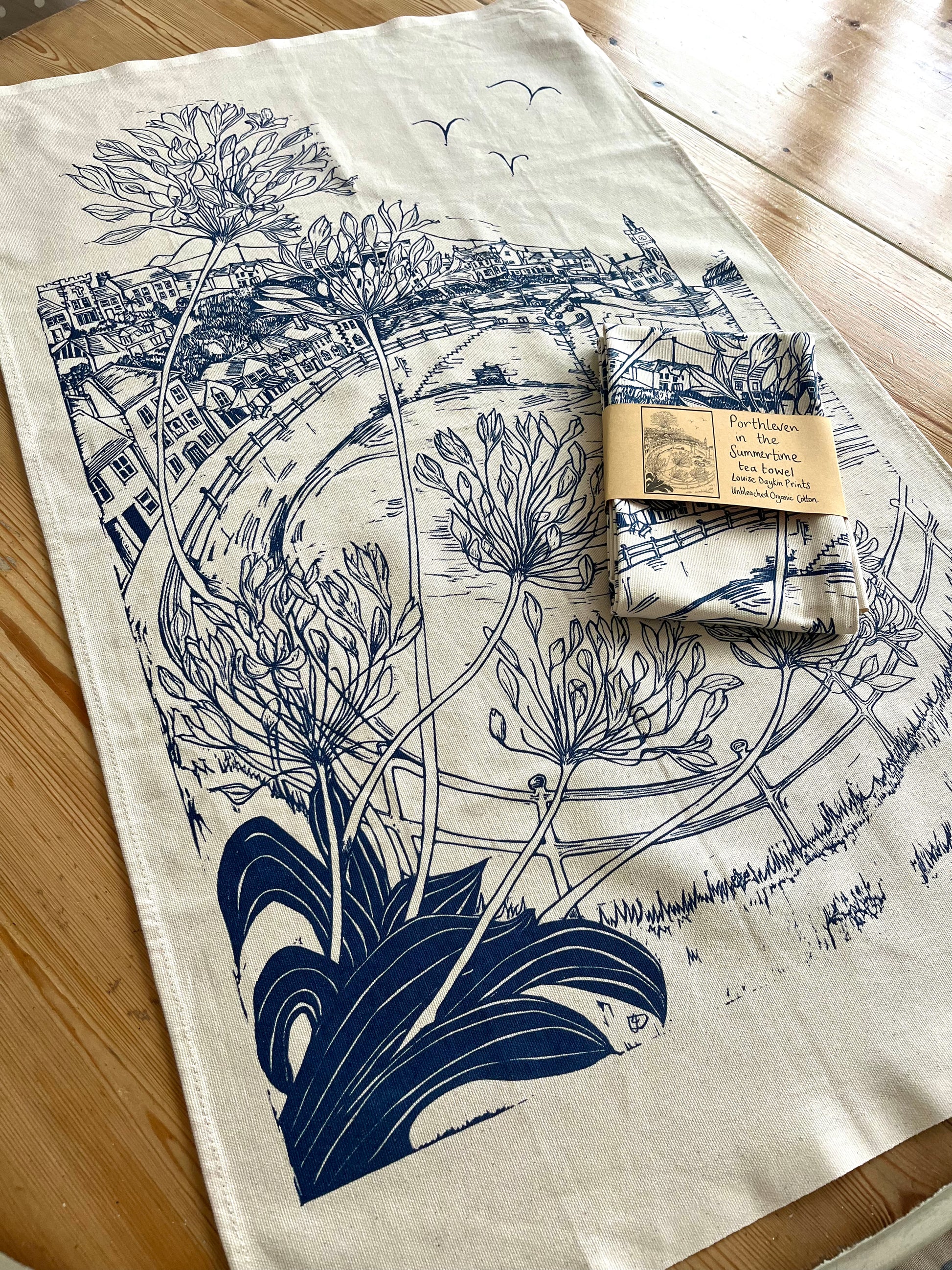 Organic cotton teatowel featuring a navy blue screen print of an original lino print of Porthleven in Cornwall. 