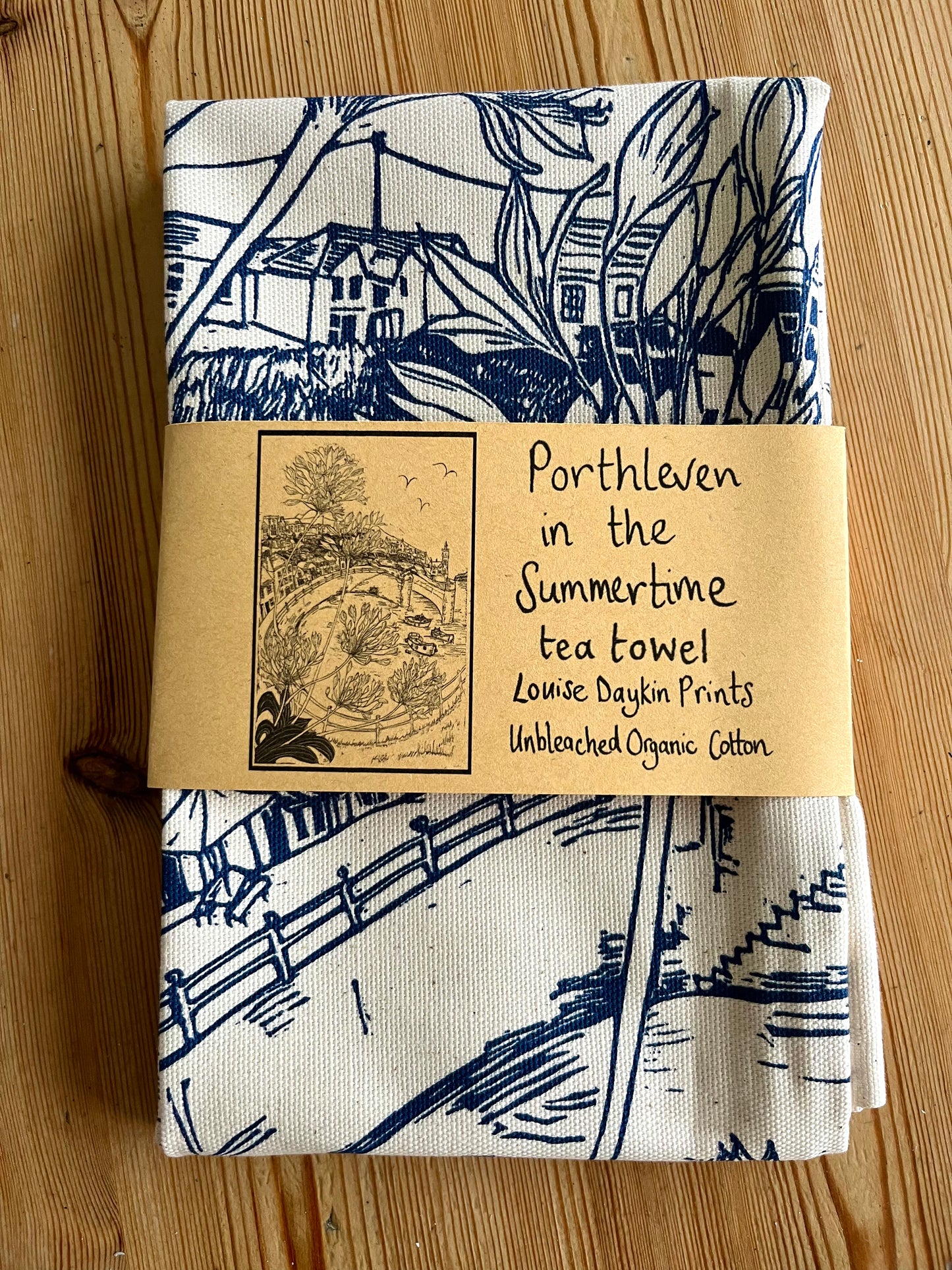 Folded "Porthleven in the Summertime" Tea towel with blue and white design and packaging 