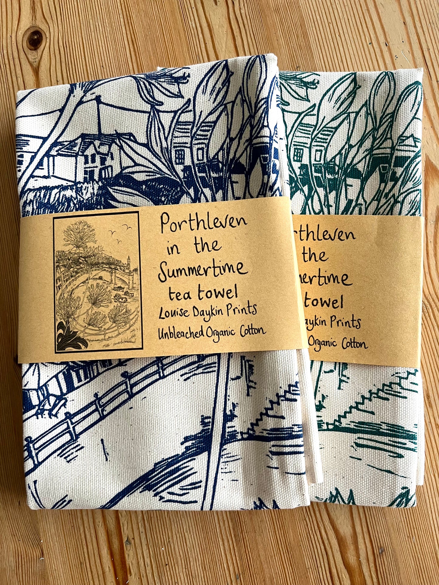 Two folded tea towels featuring a label that reads 'Porthleven in the Summertime'.
